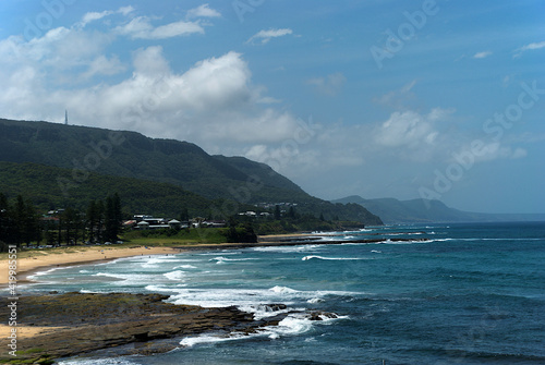 waves roll into the Wollongong coast with hill and buildings in the background
