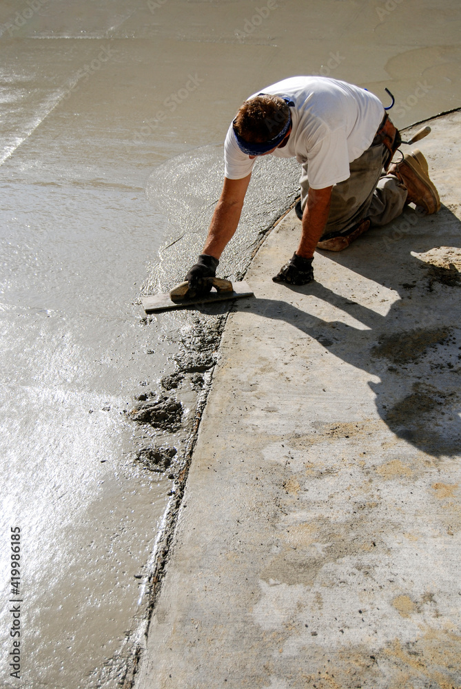 Mason smoothing freshly poured concrete slab Mason smoothing freshly poured concrete slab