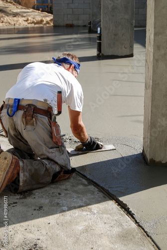 Concrete mason at work troweling fresh concrete