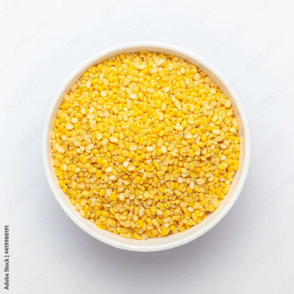 Close up of Organic yellow Gram (Vigna radiata) or split yellow moong dal on a ceramic white bowl. Top view 