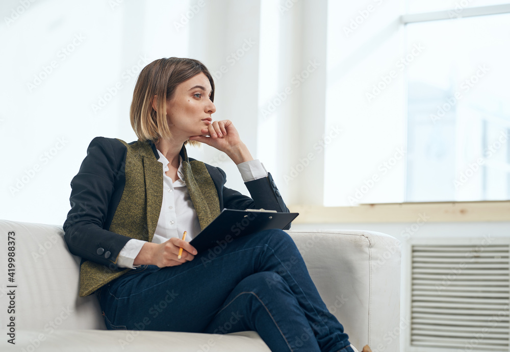 Business woman in suit with documents sitting on sofa indoors Business woman in suit with documents sitting on sofa indoors