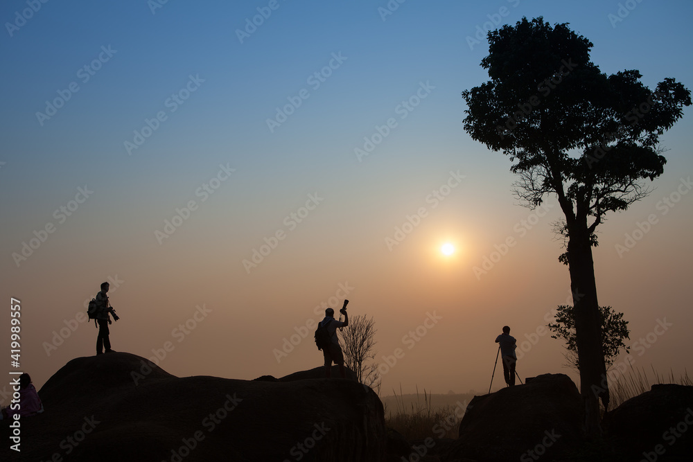 Silhouette of photographer taking picture of landscape during sunset
