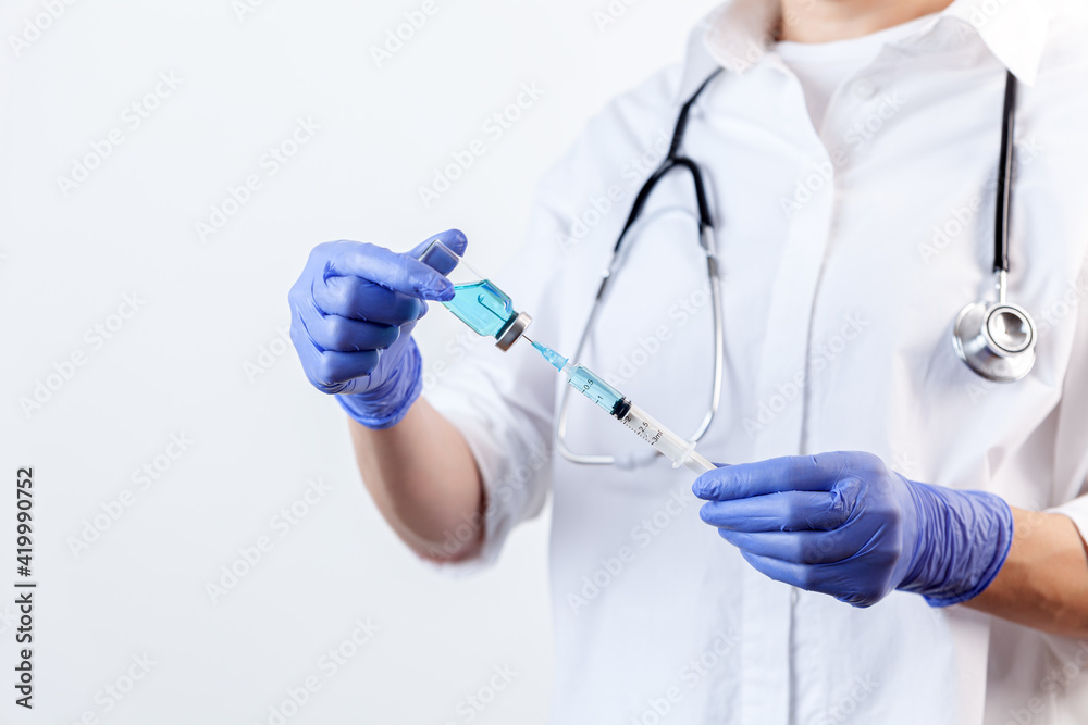 Doctor in gloves filling up syringe from bottle with vaccine, medicine Doctor in gloves filling up syringe from bottle with vaccine, medicine