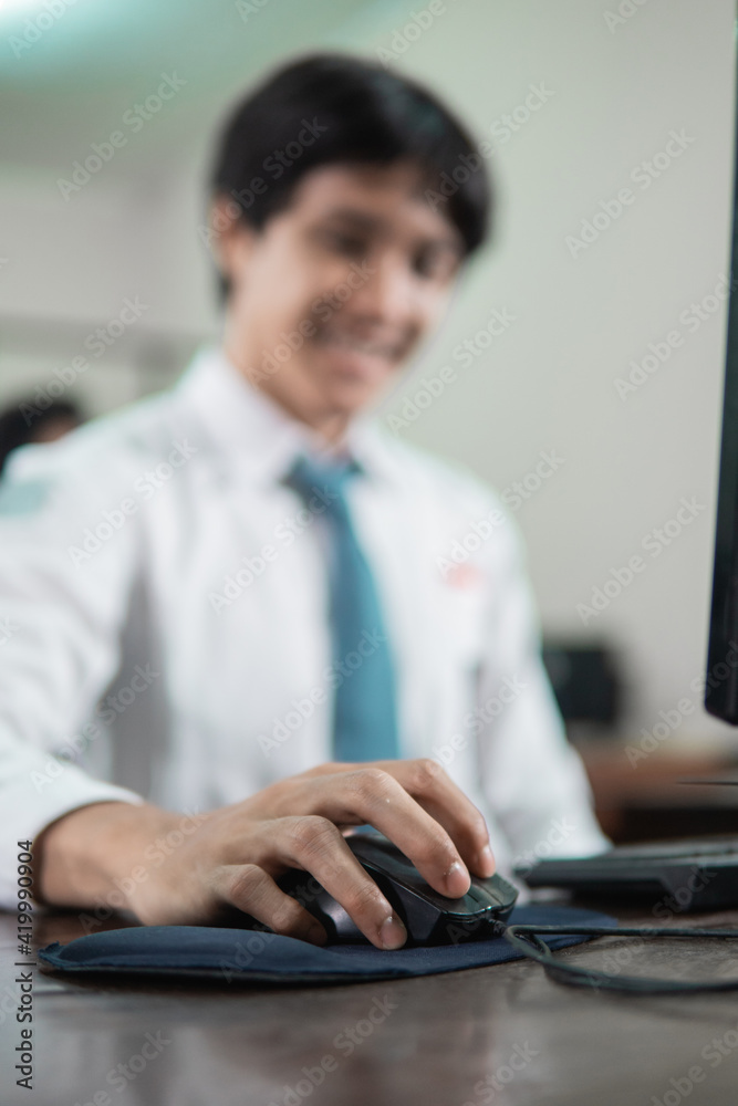 close up of a male student's hand sitting holding a computer mouse while studying close up of a male student's hand sitting holding a computer mouse while studying