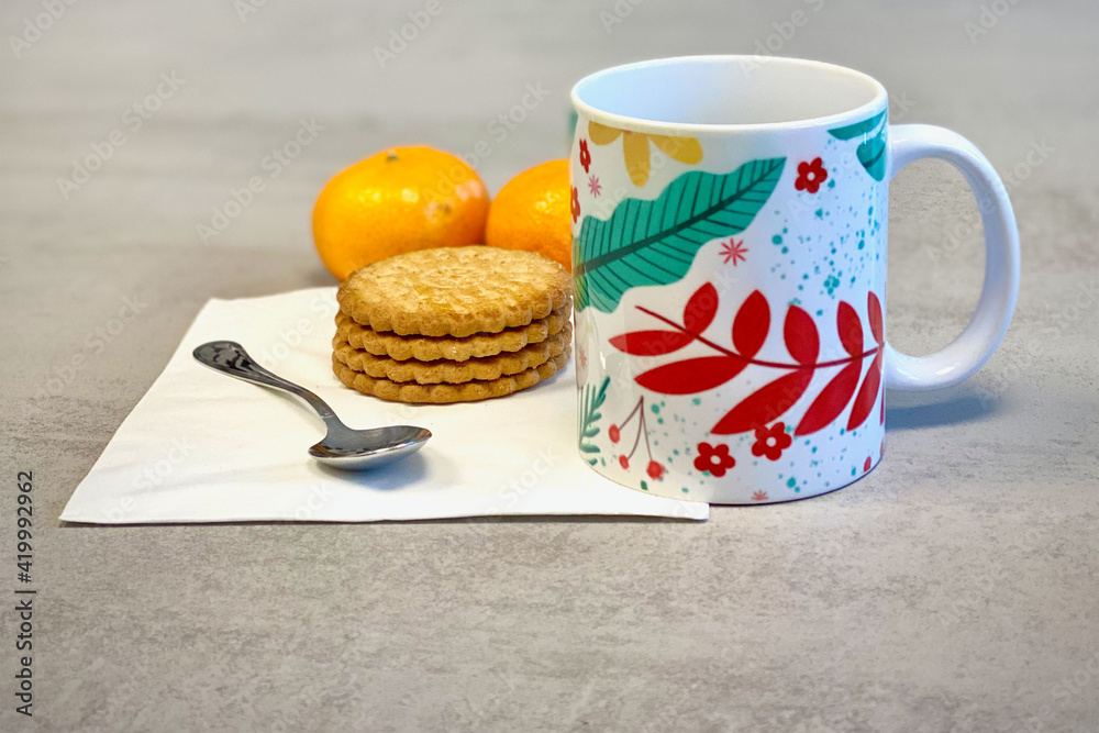 Una taza de cerámica con hojas de colores, con galletas y mandarinas preparado para el desayuno Una taza de cerámica con hojas de colores, con galletas y mandarinas preparado para el desayuno