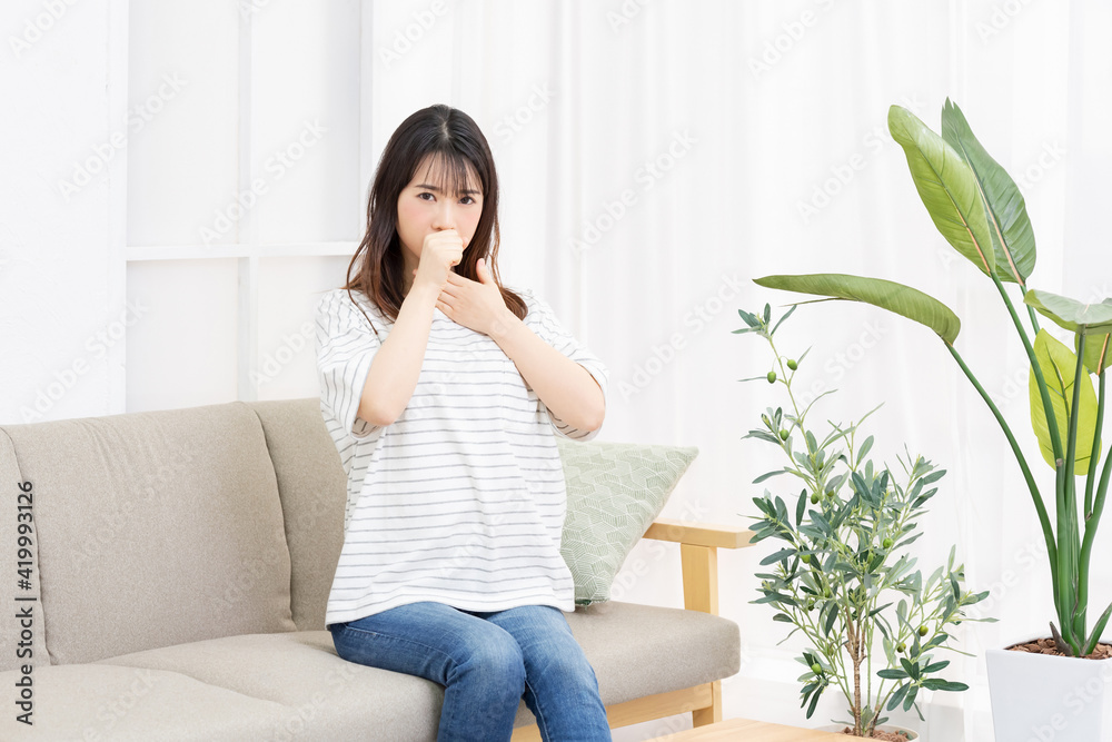 喉に手を当てる体調不良の若い女性 喉に手を当てる体調不良の若い女性