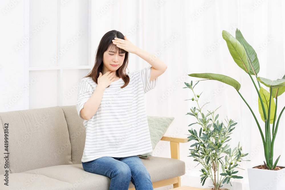 喉に手を当てる体調不良の若い女性 喉に手を当てる体調不良の若い女性