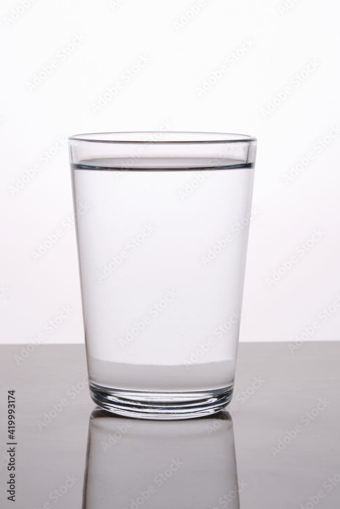 Blank glass of water captured with reflection with back lighting against light background. Blank glass of water captured with reflection with back lighting against light background.