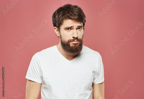 Man with a brunet beard pink background white t-shirt emotions