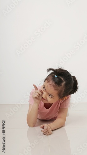 Adorable little girl pointing at wall. Isolated on white background