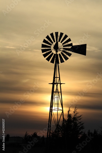 Windmill out in the country at Sunset with a colorful sky west of Nickerson Kansas USA .