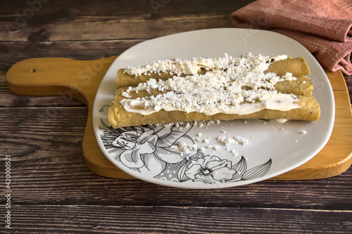 Tacos dorados called flautas with cream and cheese. Traditional Mexican food