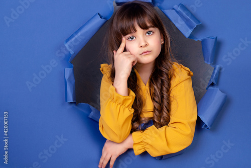 Happy emotional surprised girl in yellow dress on blue background