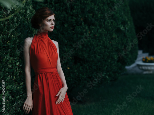 Pretty woman outdoors red dress luxury green bush walk Masquerade © SHOTPRIME STUDIO