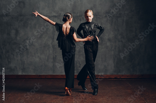 Couple in black costumes dancing in ballroom rumba dance.