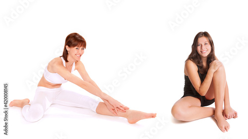 Two attractive young athletes sitting on the floor of the gym, isolated in front of white background