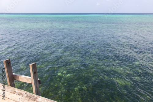 Wooden stairs to the sea with aquamarine water. Empty wooden pier at the Indian ocean coast. Tropical vacations. Tranquil seascape with stairs and steps to the water. Exotic leisure and relax. 