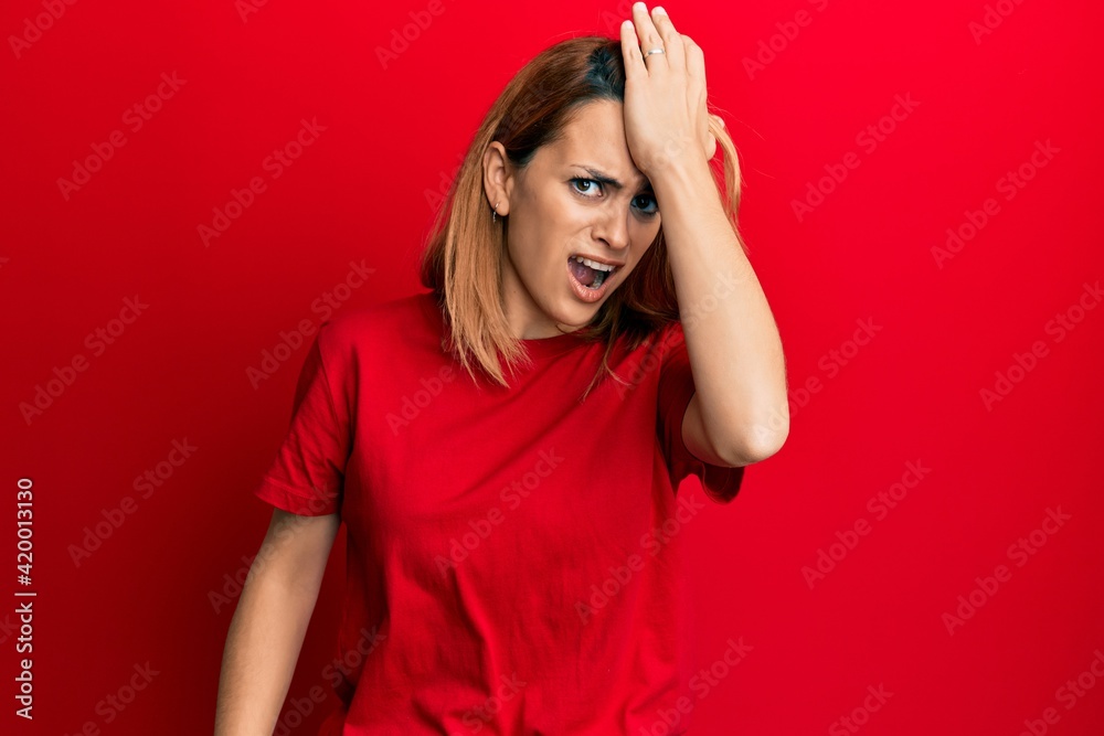 Hispanic young woman wearing casual red t shirt surprised with hand on head for mistake, remember error. forgot, bad memory concept. Hispanic young woman wearing casual red t shirt surprised with hand on head for mistake, remember error. forgot, bad memory concept.