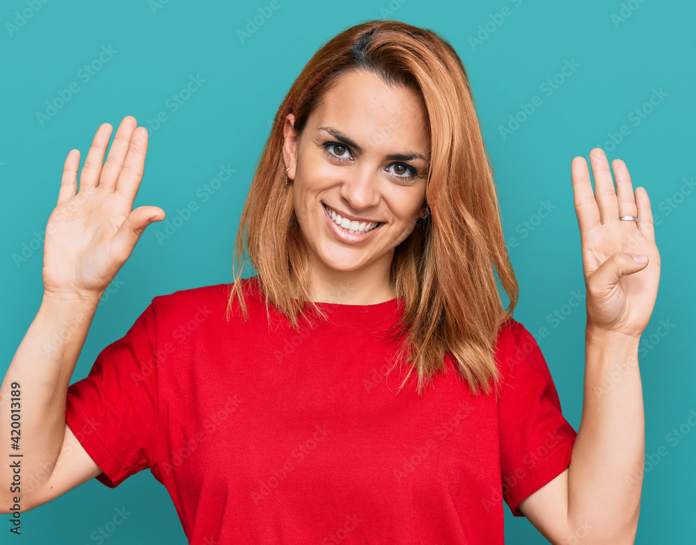 Hispanic young woman wearing casual red t shirt showing and pointing up with fingers number nine while smiling confident and happy. Hispanic young woman wearing casual red t shirt showing and pointing up with fingers number nine while smiling confident and happy.