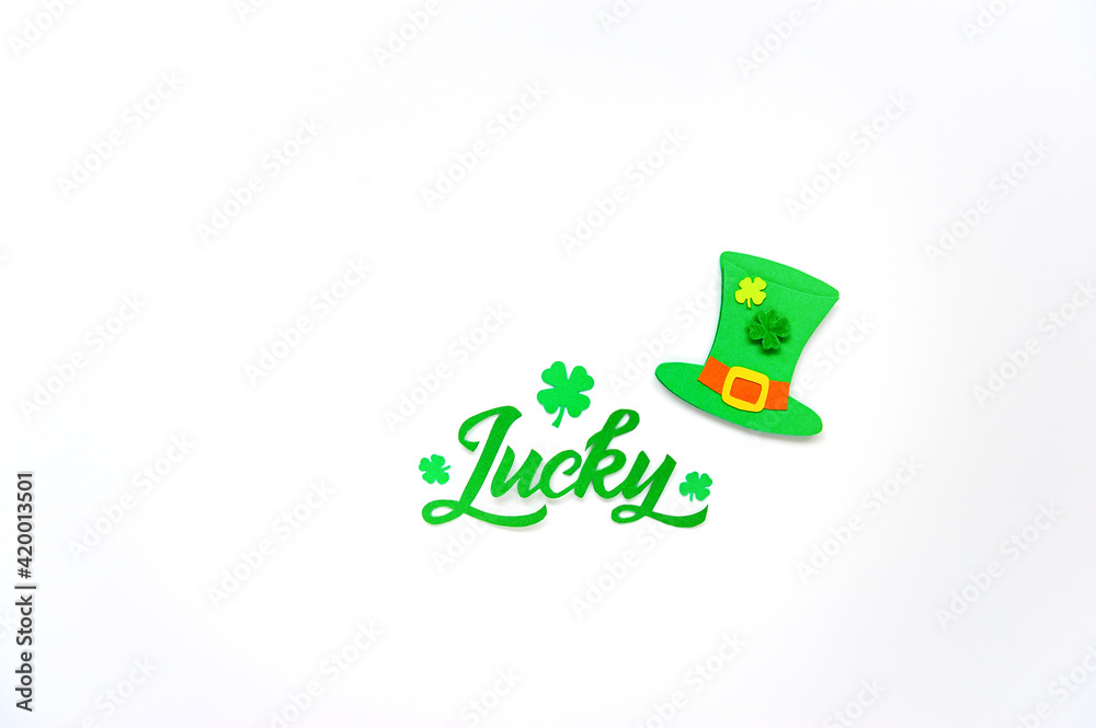 Lucky word - St. Patrick's day lettering. Brush calligraphy design with clover shamrock leaf and Leprechaun’s hat. Greeting cards. Soft focus. Top view. Lucky word - St. Patrick's day lettering. Brush calligraphy design with clover shamrock leaf and Leprechaun’s hat. Greeting cards. Soft focus. Top view.