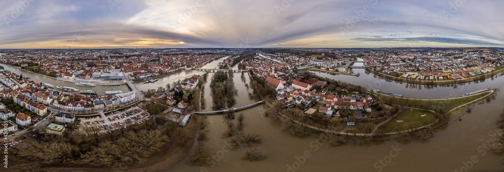 Panorama der Stadt Regensburg in Bayern mit dem Fluss Donau dem Dom und der steinernen Brücke während Hochwasser und Schneeschmelze bei Sonnenuntergang, Deutschland Panorama der Stadt Regensburg in Bayern mit dem Fluss Donau dem Dom und der steinernen Brücke während Hochwasser und Schneeschmelze bei Sonnenuntergang, Deutschland