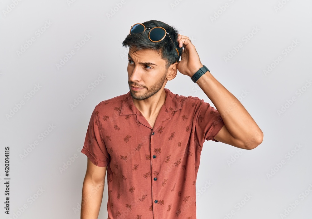 Young handsome man wearing casual summer clothes confuse and wondering about question. uncertain with doubt, thinking with hand on head. pensive concept. Young handsome man wearing casual summer clothes confuse and wondering about question. uncertain with doubt, thinking with hand on head. pensive concept.