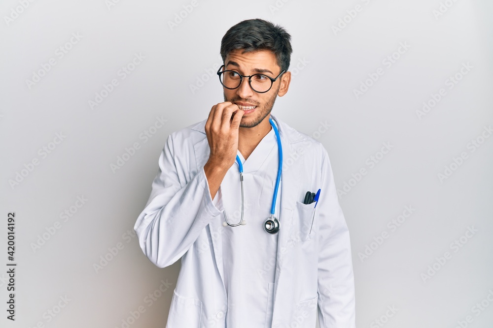 Young handsome man wearing doctor uniform and stethoscope looking stressed and nervous with hands on mouth biting nails. anxiety problem. Young handsome man wearing doctor uniform and stethoscope looking stressed and nervous with hands on mouth biting nails. anxiety problem.