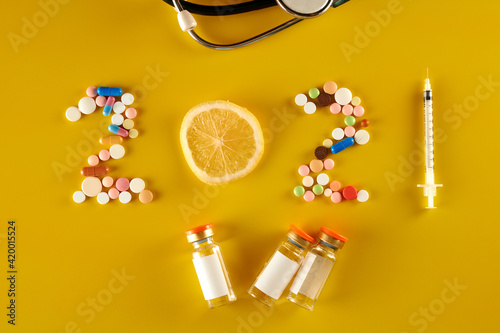 2021 from pills and a syringe on yellow background. 
citrus, phonendoscope, ampoules