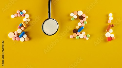 2021 from pills and a syringe on trendy yellow background. numbers from things
