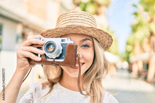 Young caucasian tourist girl smiling happy using vintage camera at street of city. © Krakenimages.com