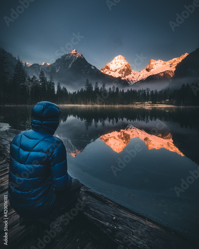 person sitting at mountain lake watching sunrise during spring