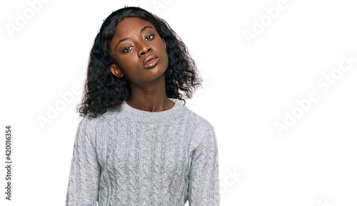 Beautiful african young woman wearing casual winter sweater relaxed with serious expression on face. simple and natural looking at the camera.