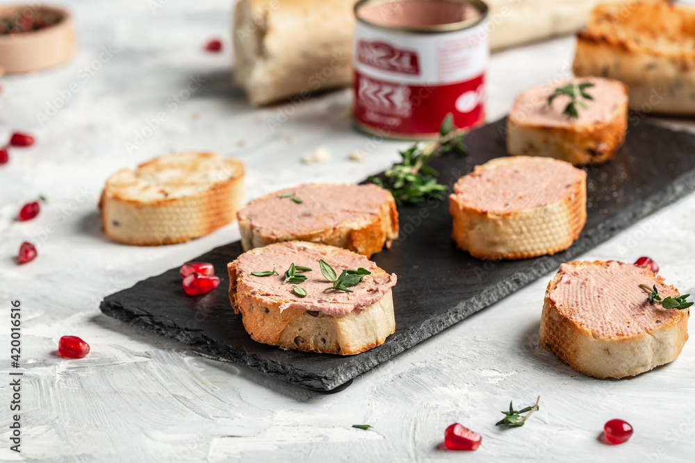 Pate spread on toasted bread with greens and pomegranate, Chicken liver pate spread. Delicious breakfast or snack on a light background, top view