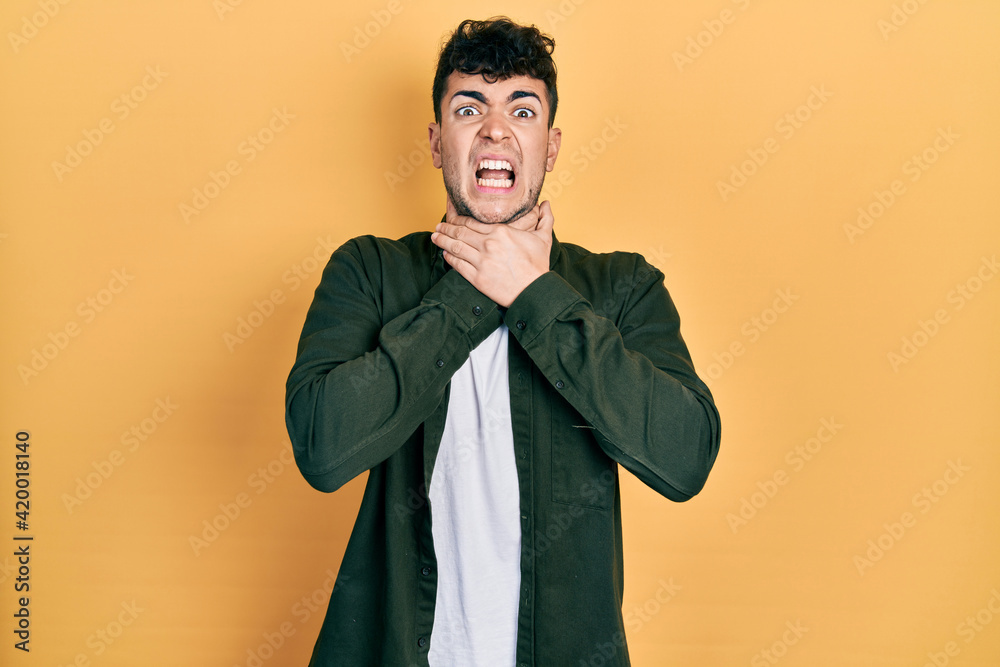 Young hispanic man wearing casual clothes shouting and suffocate because painful strangle. health problem. asphyxiate and suicide concept. Young hispanic man wearing casual clothes shouting and suffocate because painful strangle. health problem. asphyxiate and suicide concept.