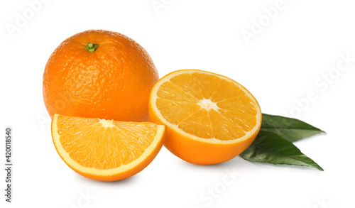 Cut and whole fresh ripe oranges with green leaves on white background