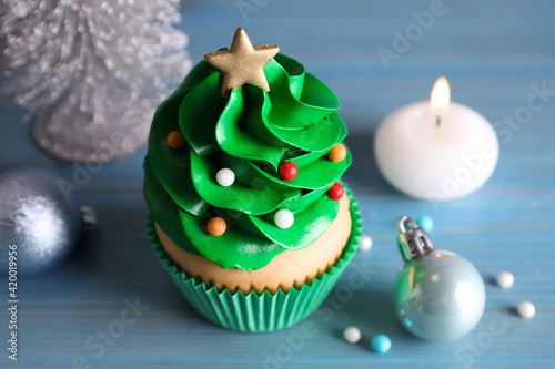 Christmas tree shaped cupcake and decor on light blue wooden table, closeup