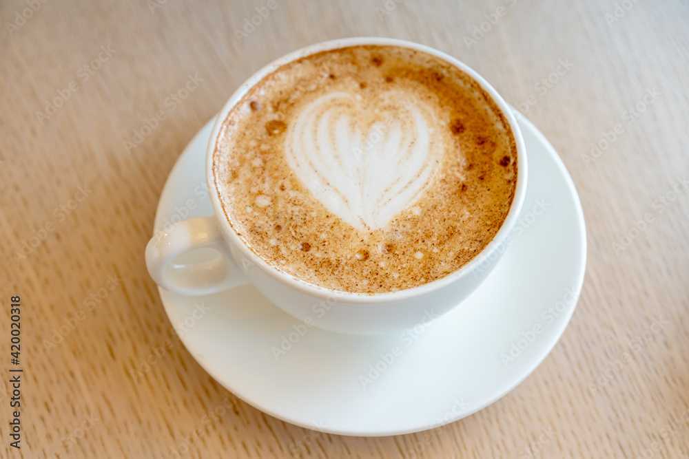 Cup of freshly brewed Cappuccino with latte art foam on a table of the cafeteria Cup of freshly brewed Cappuccino with latte art foam on a table of the cafeteria