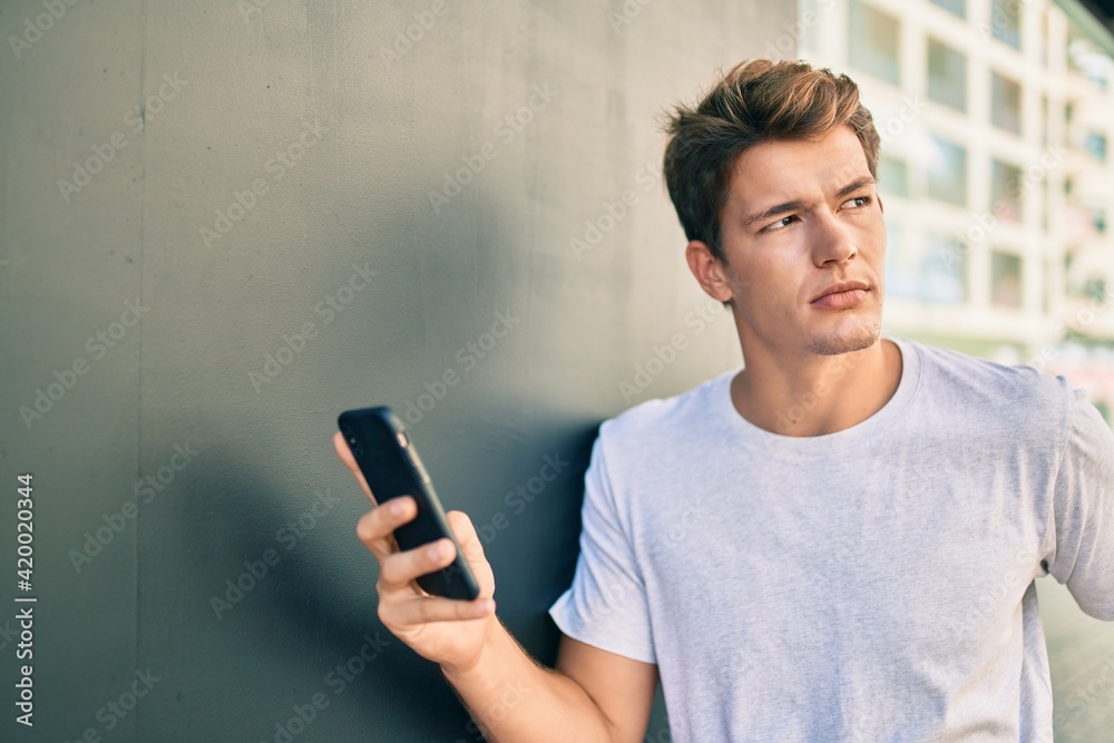 Young caucasian man with serious expression using smartphone at the city. Young caucasian man with serious expression using smartphone at the city.