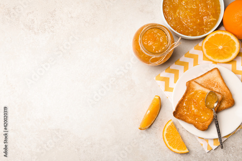 Delicious orange marmalade and toasts on light table, flat lay. Space for text