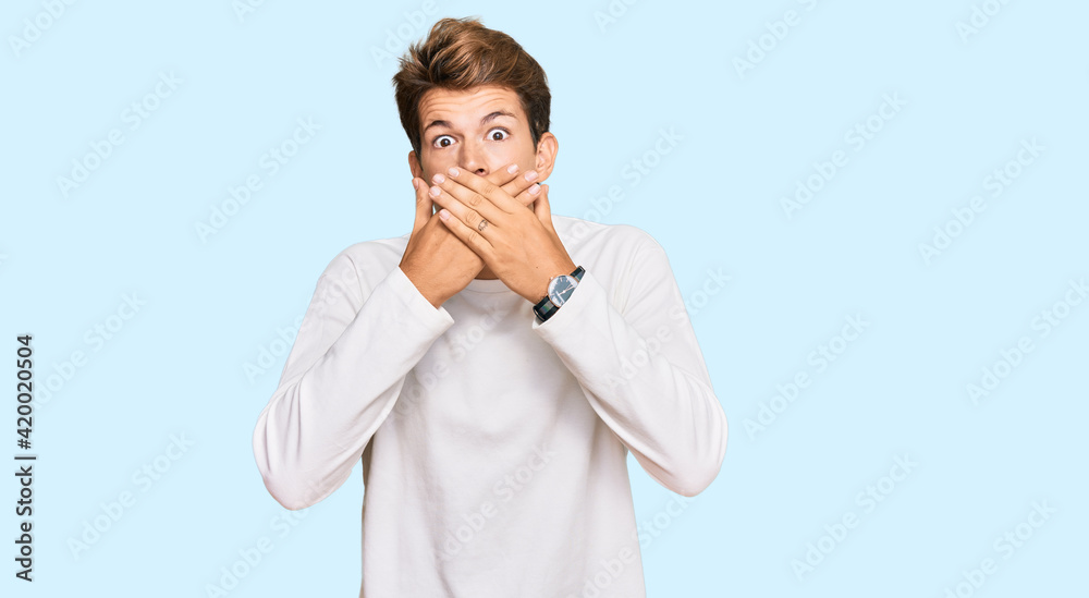 Handsome caucasian man wearing casual white sweater shocked covering mouth with hands for mistake. secret concept.