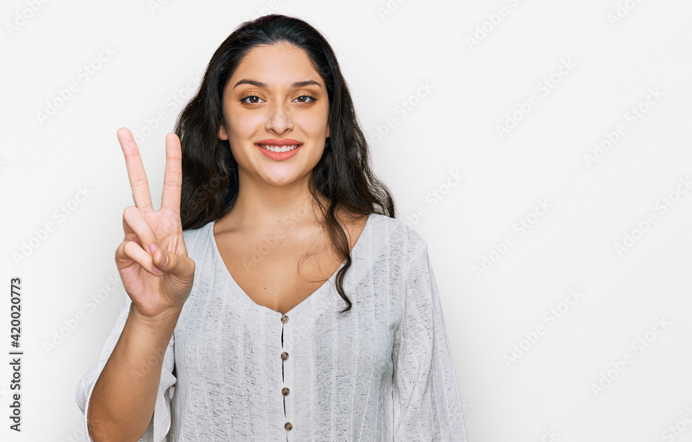 Brunette young woman wearing casual clothes showing and pointing up with fingers number two while smiling confident and happy. Brunette young woman wearing casual clothes showing and pointing up with fingers number two while smiling confident and happy.