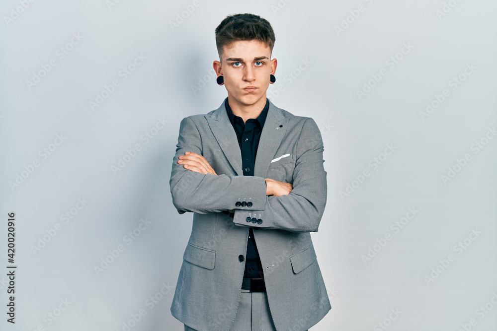 Young caucasian boy with ears dilation wearing business jacket skeptic and nervous, disapproving expression on face with crossed arms. negative person. Young caucasian boy with ears dilation wearing business jacket skeptic and nervous, disapproving expression on face with crossed arms. negative person.