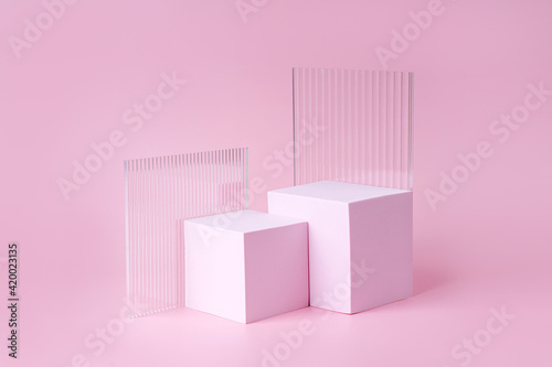 Geometric shapes podium for product display. Monochrome platform with ribbed acrylic sheets on pink background. Stylish background for presentation. Minimal style.