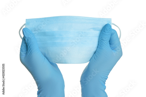 Doctor in latex gloves holding medical mask on white background, closeup