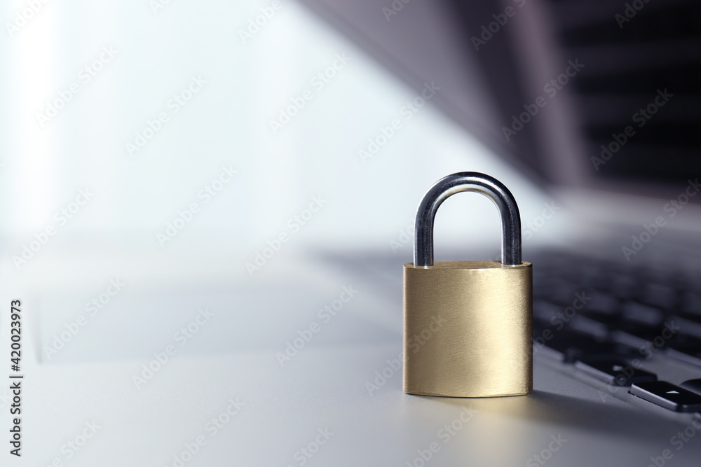 Naklejka premium Metal padlock on laptop keyboard, space for text. Cyber security concept