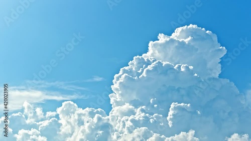 Timelapse of white cumulus clouds rolling in the blue sky with sunlight photo