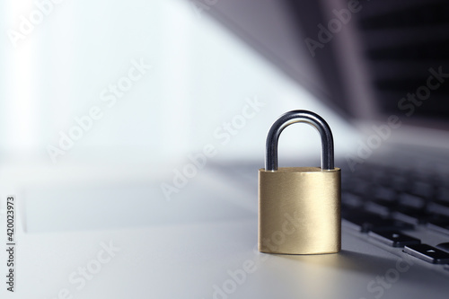 Metal padlock on laptop keyboard, space for text. Cyber security concept