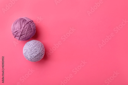 Soft colorful woolen yarns on pink background  flat lay. Space for text