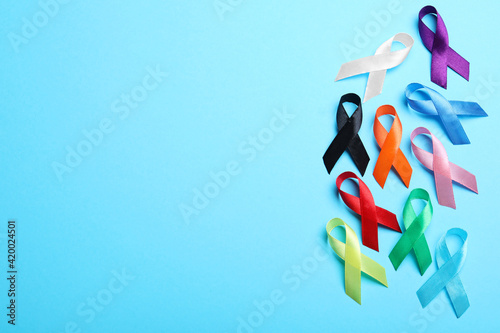 Colorful ribbons on light blue background, flat lay with space for text. World Cancer Day photo