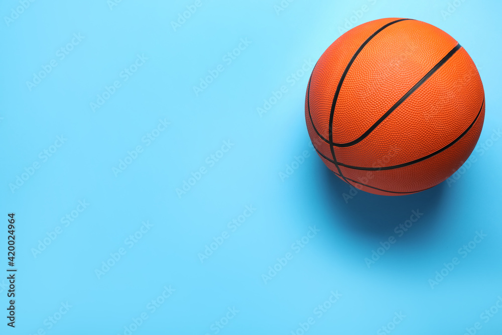 Orange ball on light blue background, top view with space for text. Basketball equipment
